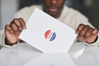 Pessoa deposita uma cédula eleitoral em uma urna durante uma votação.