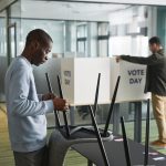 Homens preparando cabines de votação em uma seção eleitoral interna.