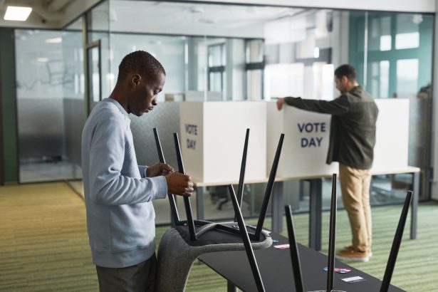 Homens preparando cabines de votação em uma seção eleitoral interna.